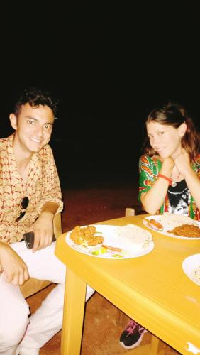 a man and woman sitting at a table with plates of food at The Mountain View Home Stay in Khajurāho