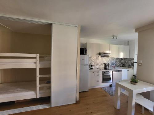 - une cuisine blanche avec des lits superposés et une table dans l'établissement Superbe T2 en centre ville au calme à deux pas du marché, à Cavalaire-sur-Mer