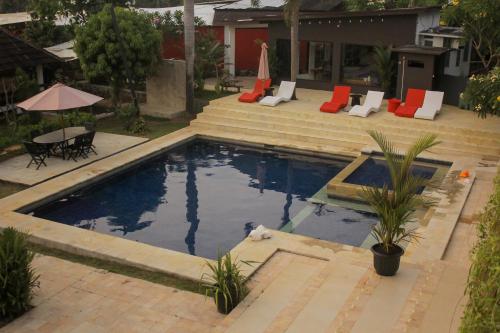 a pool with chairs and a table in a yard at Lucca Resort & Residence in Jepara