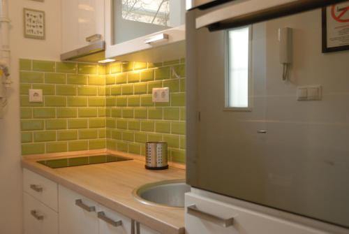 a kitchen with a sink and green tiles on the wall at Mintage Apartment /Former Mirage Apartment in Budapest