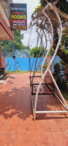 a metal bench sitting on a sidewalk next to a sign at Tony's Garden House Back Packers inn in Jaffna