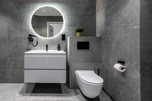a bathroom with a toilet and a sink and a mirror at InPoint Apartments G15 near Old Town & Kazimierz District & Optional Paid Parking in Kraków