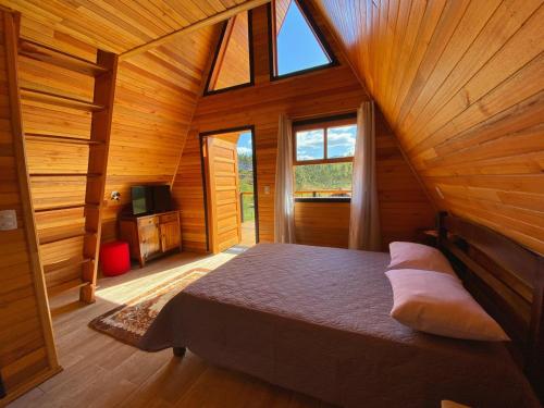 a bedroom with a bed in a wooden cabin at Pousada Sítio Elias - Chalé 1 in Louro Müller