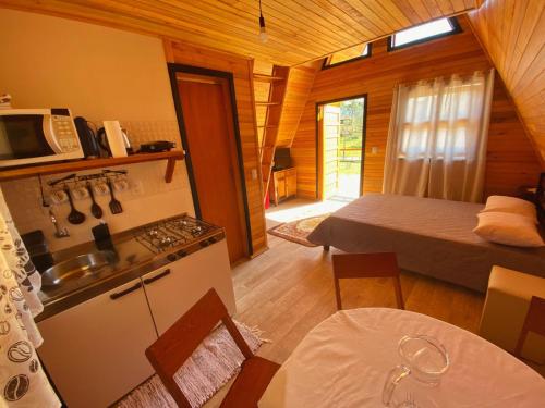 a room with a kitchen and a bedroom with a bed at Pousada Sítio Elias - Chalé 1 in Louro Müller