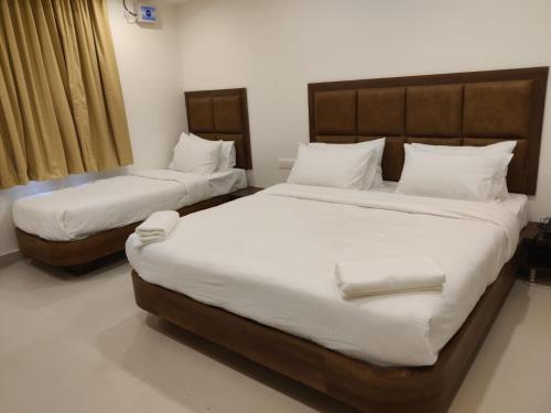 two beds in a room with white sheets at Relax Inn in Bengaluru