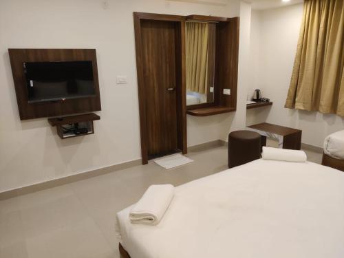 um quarto de hotel com uma cama e uma televisão de ecrã plano em Relax Inn em Bangalore
