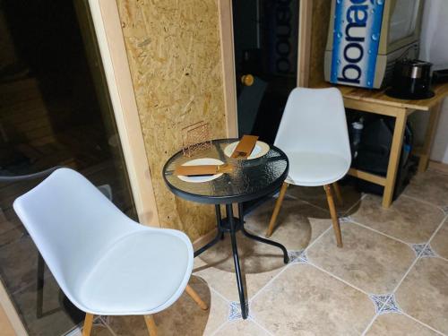 two white chairs and a table in a room at MMA apartament & sauna in Martinai