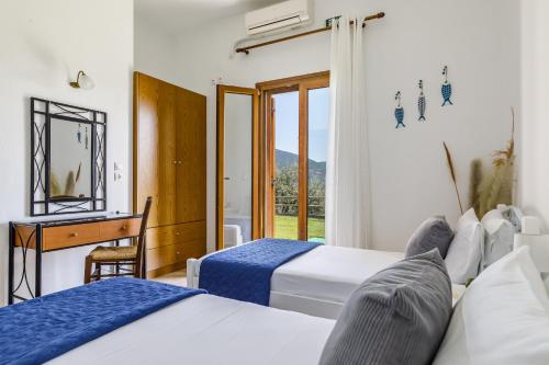 a bedroom with two beds and a desk and a window at Villa Chrysalis in Skopelos Town
