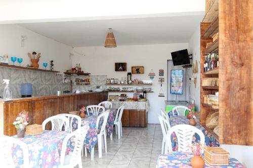 ein Esszimmer mit weißen Stühlen und eine Küche in der Unterkunft Estalagem Vovô Elias in São Miguel dos Milagres