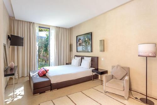 Habitación de hotel con cama y silla en Al Maaden Ryad 69 a Marrakesh en Marrakech