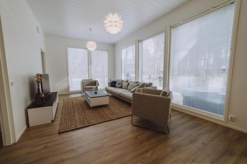 a living room with a couch and chairs and windows at Villa Dyyni Yyteri in Pori