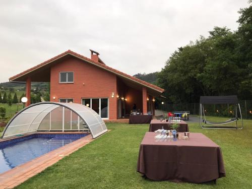 ein Haus mit einem Tisch vor einem Pool in der Unterkunft Villa Bosque Albite in Llanera