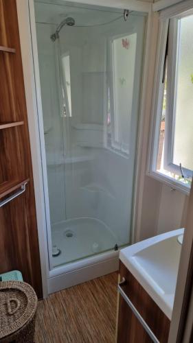 une salle de bain avec douche et lavabo dans l'établissement Camping Oasis Village, à Puget-sur Argens