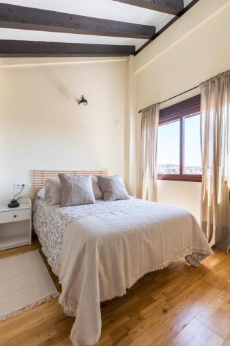 a white bedroom with a large bed and a window at Casa Rural Sierramagna de 2 Dormitorios in El Ronquillo