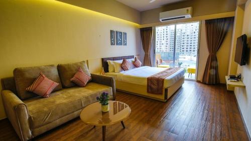 um quarto de hotel com um sofá, uma cama e uma mesa em Weekend Address managed by Global Hospitality em Surat