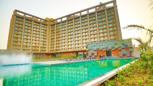 a hotel with a swimming pool in front of a building at Weekend Address managed by Global Hospitality in Surat