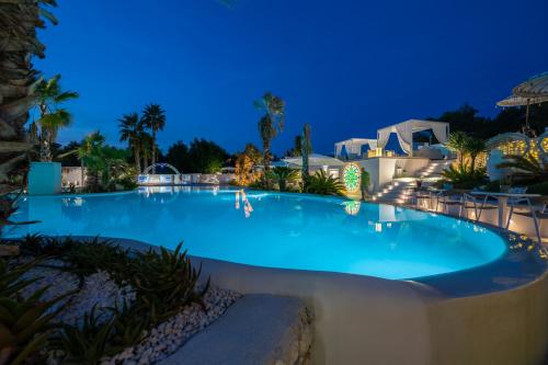 uma grande piscina à noite com cadeiras à volta em Malia Village em Vieste