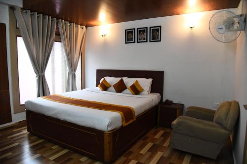 a bedroom with a large bed and a chair at PHIBHA VILLA in Shillong