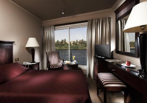 a hotel room with a bed and a desk and a window at Jaz Crown Jubilee Nile Cruise - Every Thursday from Luxor for 07 & 04 Nights - Every MondayFrom Aswan for 03 Nights in Luxor