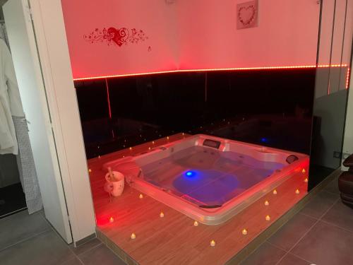 une baignoire jacuzzi dans une chambre avec des lumières rouges dans l'établissement TMspa, à Saintry-sur-Seine
