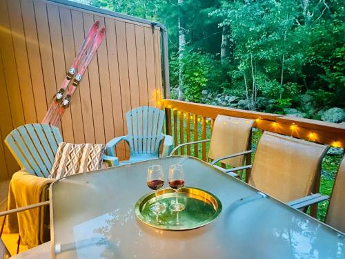een tafel met twee glazen wijn op een balkon bij Redwood Retreat in Windham - Pool! Tennis! in Windham