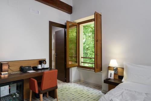 a hotel room with a desk and a bed and a window at Elda Hotel in Vico del Gargano