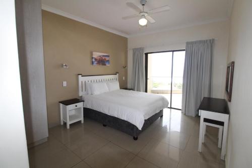 Schlafzimmer mit einem Bett, einem Schreibtisch und einem Fenster in der Unterkunft Saints View Resort Unit 23 in Uvongo Beach