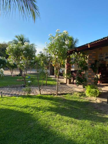 a yard with green grass and a building and trees at Pousada Sitio Parque dos Lençóis in Barreirinhas
