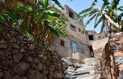 a stone building next to a stone wall at نزل حارة المسفاة Harit AL Misfah Inn in Misfāh
