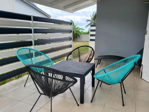 聖羅斯的住宿－L'Aurielle, Tout le confort à 500m de la plage，庭院配有三把椅子和一张黑色的桌子及椅子