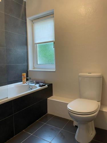 a bathroom with a white toilet and a bath tub at Gowanlea Guest House in Balloch