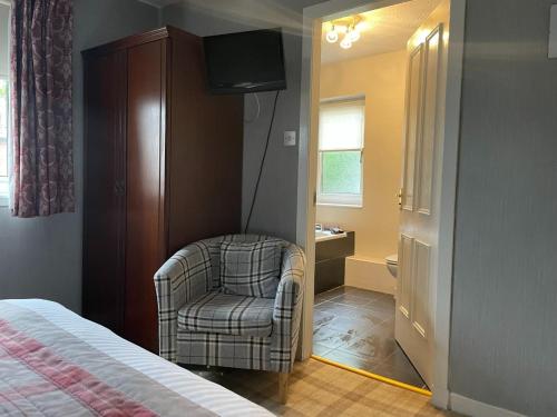una camera da letto con una sedia e una televisione di Gowanlea Guest House a Balloch