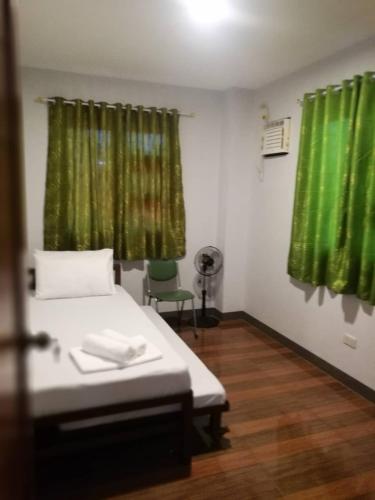 Piccola camera con letto e tende verdi di Rancho Lodge Hometel a Sorsogon