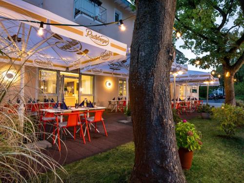 a patio with tables and chairs under an umbrella at Kristallhotel Fettehenne in Leverkusen