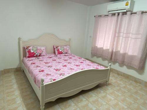a bedroom with a bed with pink sheets and a window at Pani House Hatyai 1 in Hat Yai