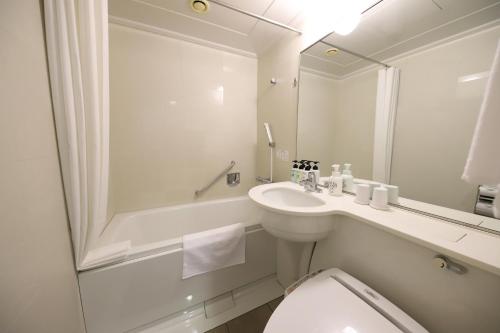 a bathroom with a sink and a toilet and a mirror at Smile Hotel Osaka Yotsubashi in Osaka