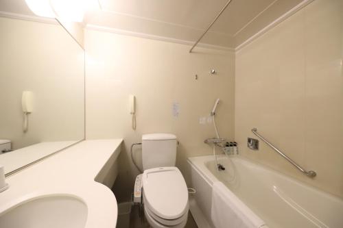 a white bathroom with a toilet and a bath tub at Smile Hotel Osaka Yotsubashi in Osaka