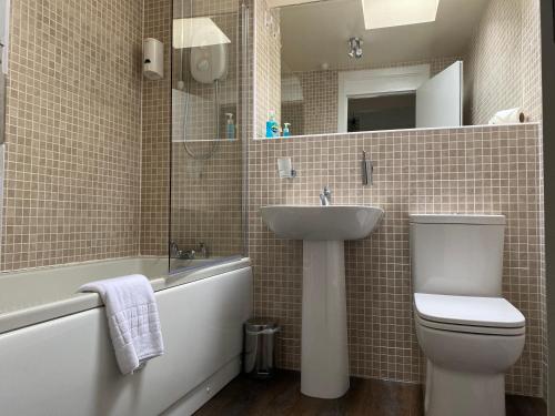 a bathroom with a toilet and a sink and a tub at The Fort Hotel in Dundee