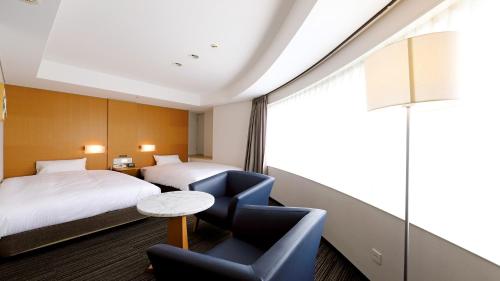 una habitación de hotel con 2 camas y una silla en Smile Hotel Osaka Yotsubashi en Osaka