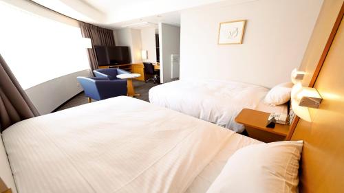a hotel room with two beds and a desk at Smile Hotel Osaka Yotsubashi in Osaka