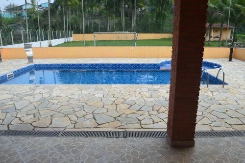 a swimming pool with a stone floor and a pole at Sítio Oliveira in Itariri