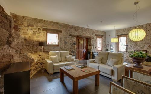 una sala de estar con muebles blancos y una pared de piedra. en Posada Real La Almazuela, en Montenegro de Cameros