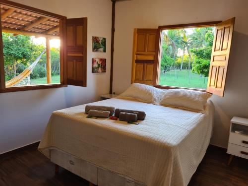 a bedroom with a large bed with a window at Casa Marfim - Privacidade, charme e conforto à 50m do rio in Caravellas