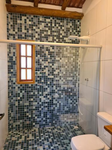 a bathroom with a shower with a toilet and blue tiles at Casa Marfim - Privacidade, charme e conforto à 50m do rio in Caravellas