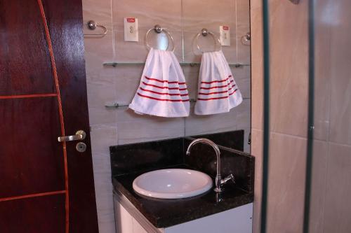 a bathroom with a sink and two towels on a wall at Casa Lua Nova na Praia de Peroba, Maragogi in Maragogi