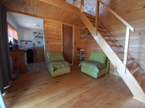 a room with two chairs and a staircase in a house at Hermosa cabaña con vista al lago Vichuquén in Vichuquén