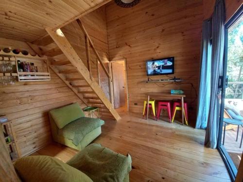 Sala de estar de una cabaña de madera con TV y mesa en Hermosa y cómoda cabaña con vista al lago, en Vichuquén