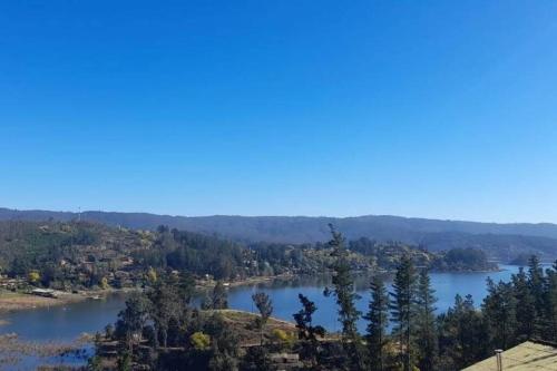 a view of a lake with trees and mountains at Hermosa cabaña con vista al lago Vichuquén in Vichuquén