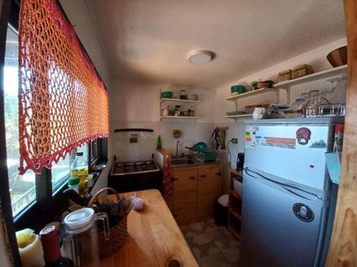a kitchen with a white refrigerator and a wooden table at Hermosa cabaña con vista al lago Vichuquén in Vichuquén