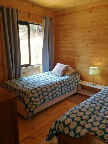 a bedroom with two beds in a log cabin at Hermosa cabaña con vista al lago Vichuquén in Vichuquén